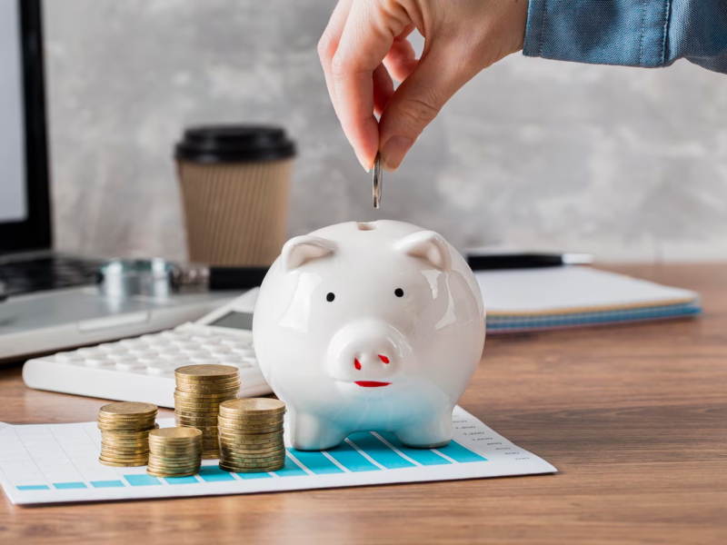 a person adding coin to piggy bank